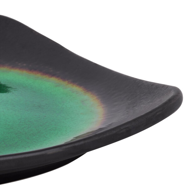 A close up of a Libbey Hakone square stoneware plate with round detailing and a black and green rainbow rim.