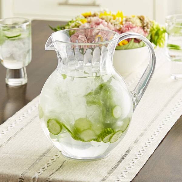 A clear plastic pitcher of water with cucumber slices and ice.