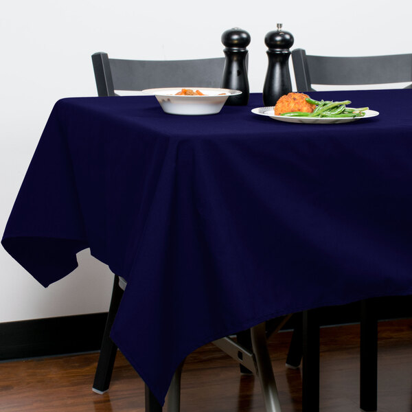 A table with a navy blue Intedge tablecloth and a plate of food.