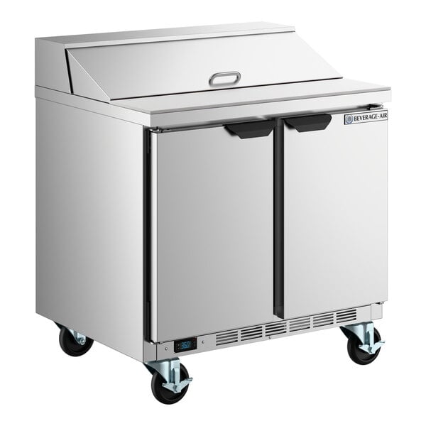 A stainless steel two-door refrigerated sandwich prep table on wheels.