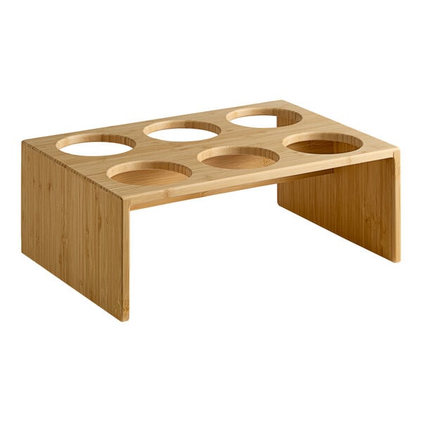 A bamboo display rack with six circular cutouts designed to hold flatware or condiment cylinders horizontally.