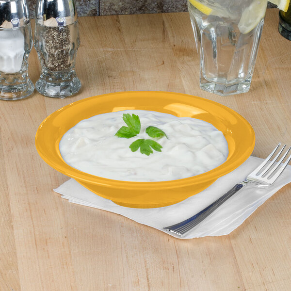 A yellow Thunder Group melamine soup bowl on a table with food in it.