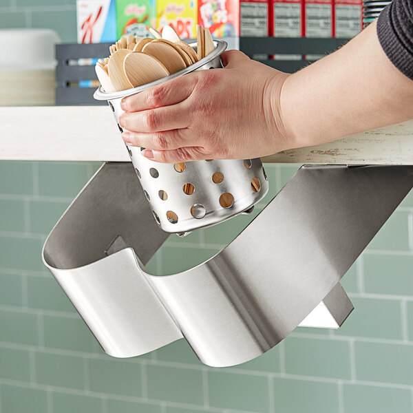 A hand placing spoons in a Steril-Sil stainless steel flatware organizer.