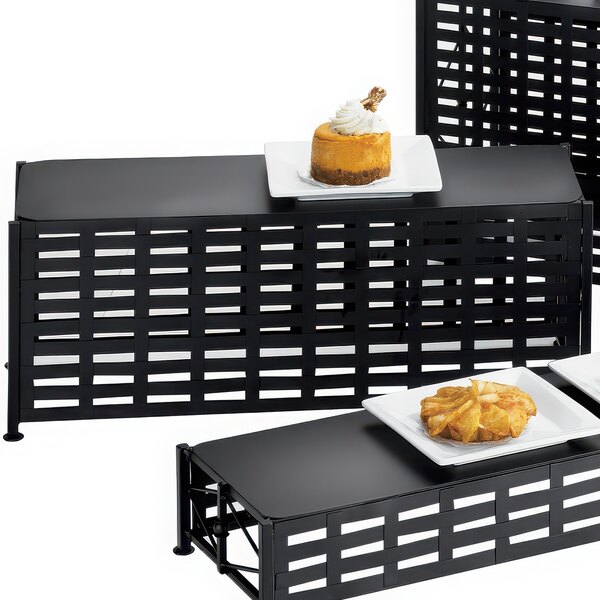 A black rectangular lattice riser with food on a table.
