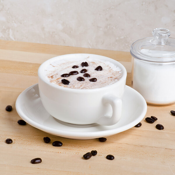 A white Tuxton jumbo cappuccino cup filled with coffee and topped with brown beans.