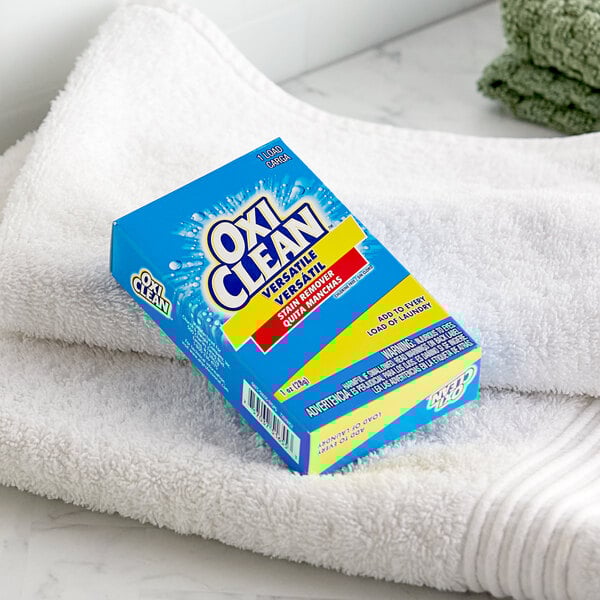 A blue box of OxiClean powder on a white towel.