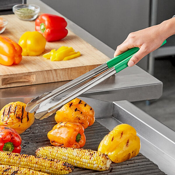 A person using Vollrath stainless steel tongs with green Kool-Touch handle to serve corn on the cob.