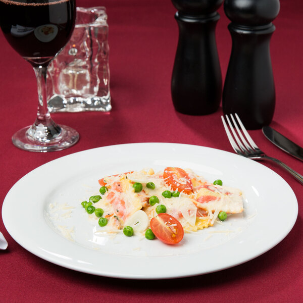 A Tuxton Alaska bright white china plate with pasta, tomatoes, and peas on it.