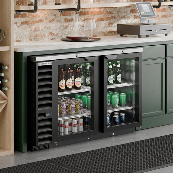 A black counter height glass door back bar refrigerator filled with assorted beverages.