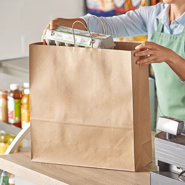 A woman holding a Duro brown paper shopping bag full of groceries.