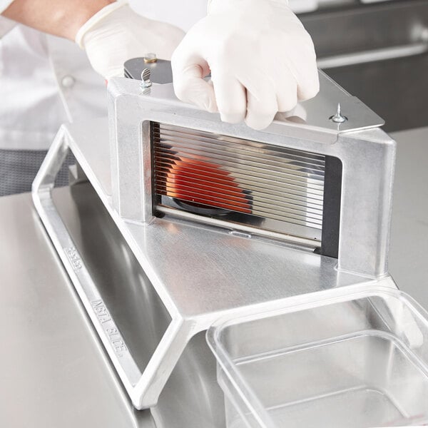 A person using a Vollrath InstaSlice machine to cut fruit.