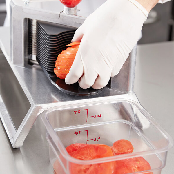 A person using a Vollrath vegetable slicer to cut tomatoes.