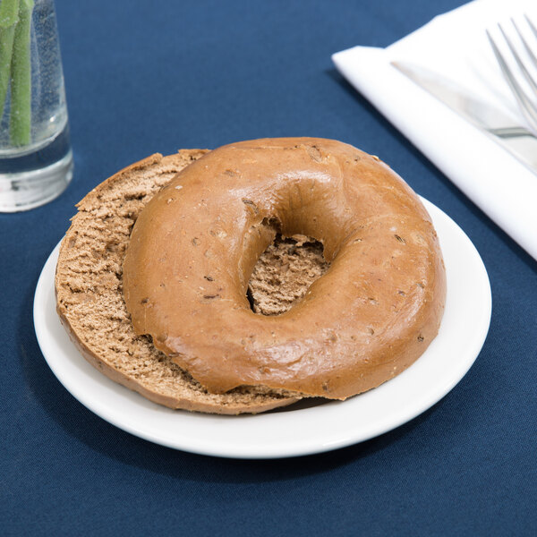 A Tuxton Alaska bright white wide rim china plate with a bagel on it.