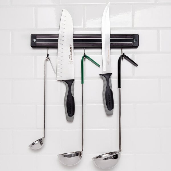 Magnetic knife holder on wall with knives and ladles attached