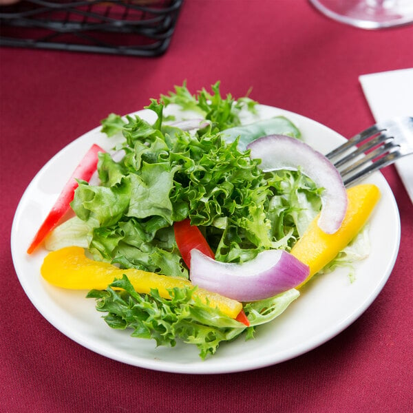 A Tuxton Venice ivory china plate with a salad and a fork.