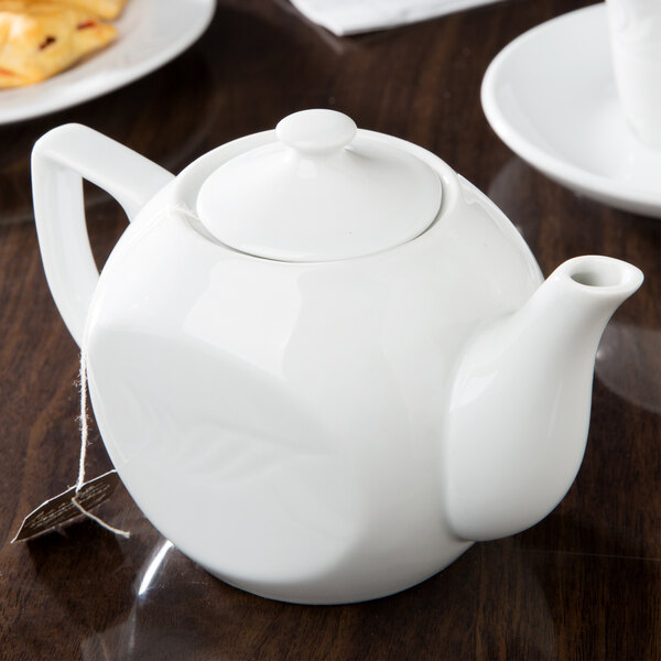 A CAC white porcelain teapot on a table.