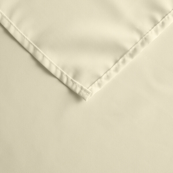A close up of an ivory rectangular Intedge cloth table cover.