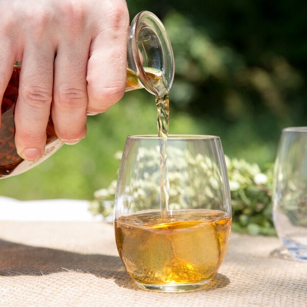 A hand pouring brown liquid into a Chef & Sommelier rocks glass.