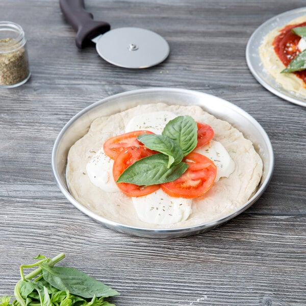 An American Metalcraft deep dish pizza pan with a pizza topped with tomatoes, basil, and cheese.