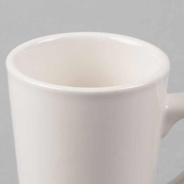 A close-up of a white Tuxton Alpine china mug with a handle.