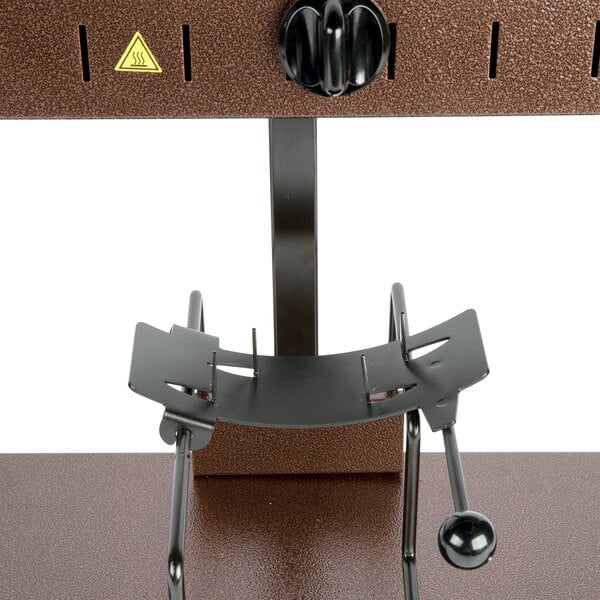 A black metal Bron Coucke Raclette Machine stand with a metal object on it.