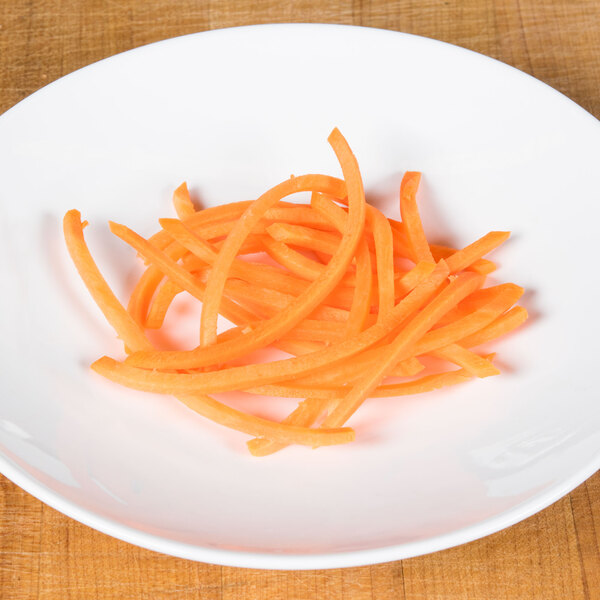 A pile of julienne cut carrots on a wooden plate.