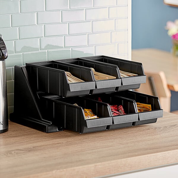 A black Cambro 2-tier stand with condiment bins on a counter.