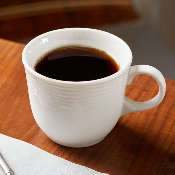 A white porcelain tea cup filled with coffee on a table.