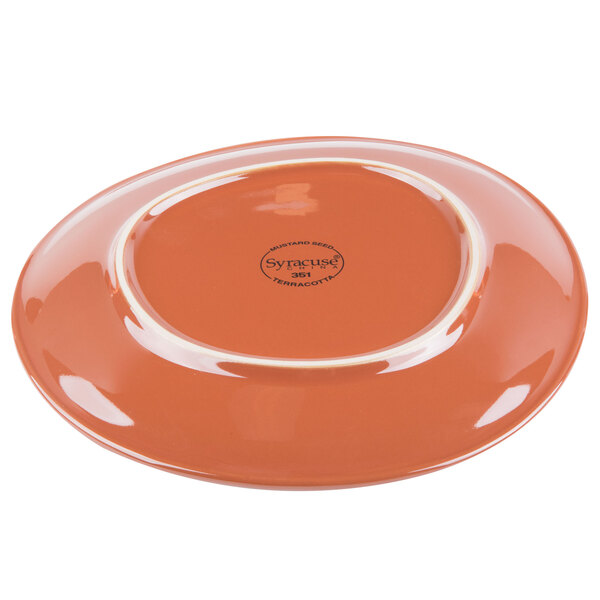 A Libbey mustard seed yellow terracotta plate with a white rim on a table.