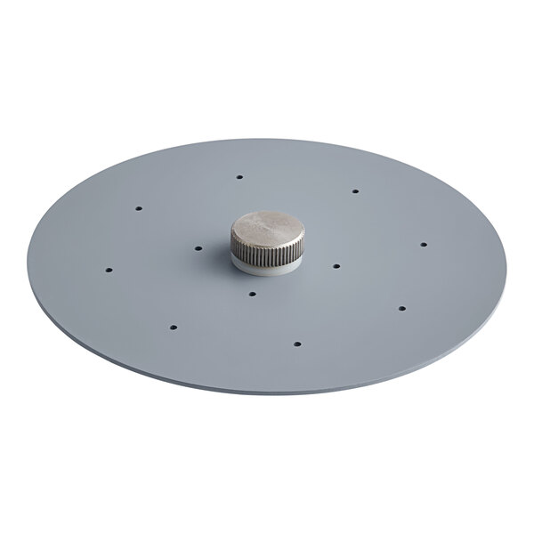 A grey circular metal plate with holes and a silver knob.