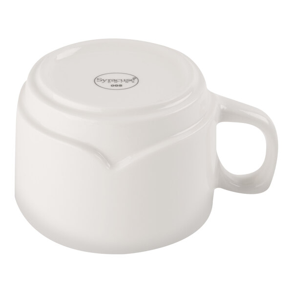 A white porcelain cup is shown upside down, displaying its handle and the manufacturer's mark on the bottom.