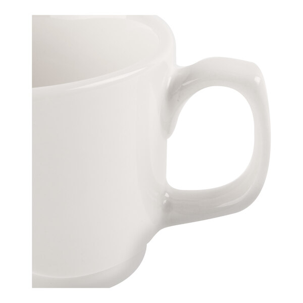 A close-up view of a white ceramic cup with a handle.