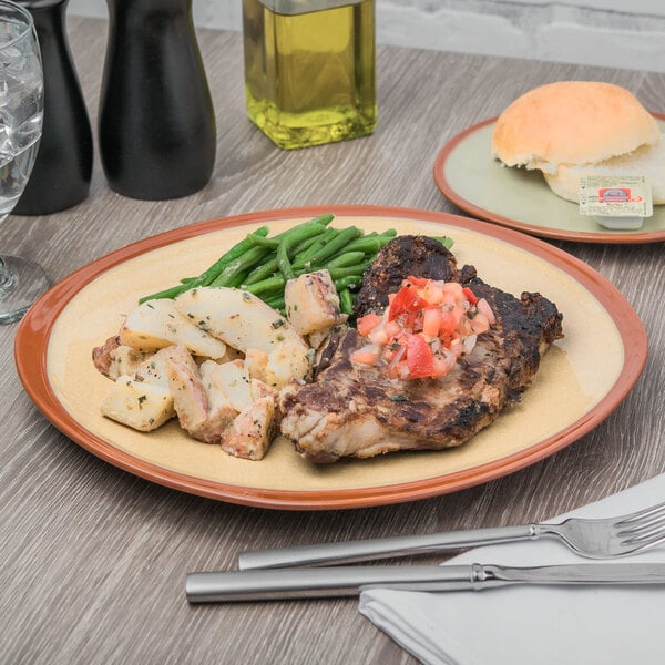 A Libbey Terracotta Mustard Seed Yellow plate with meat, potatoes, and green beans on a table.