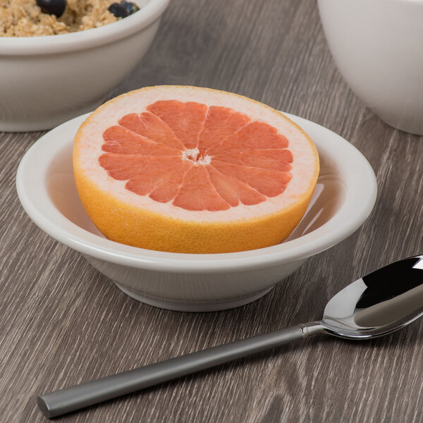 A Libbey ivory porcelain bowl with a half of a grapefruit inside on a table.