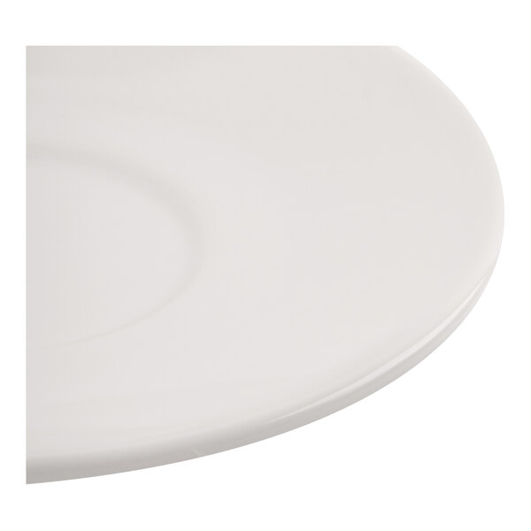 A close-up view of a smooth, round, ivory-colored porcelain saucer.