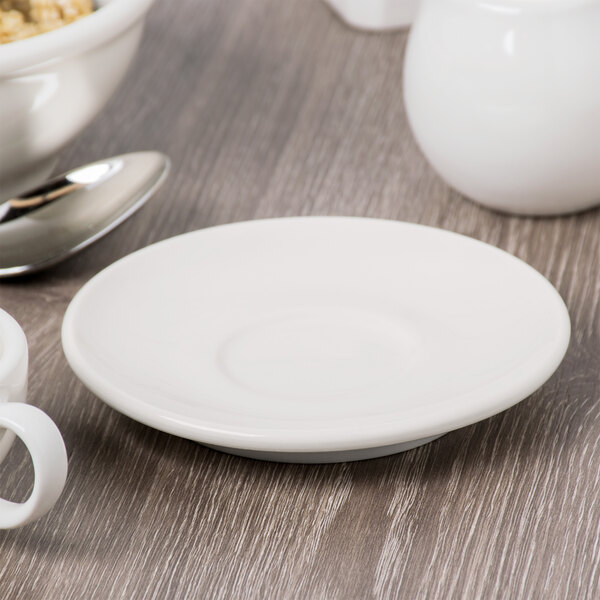 A Libbey ivory porcelain saucer under a white cup on a table.