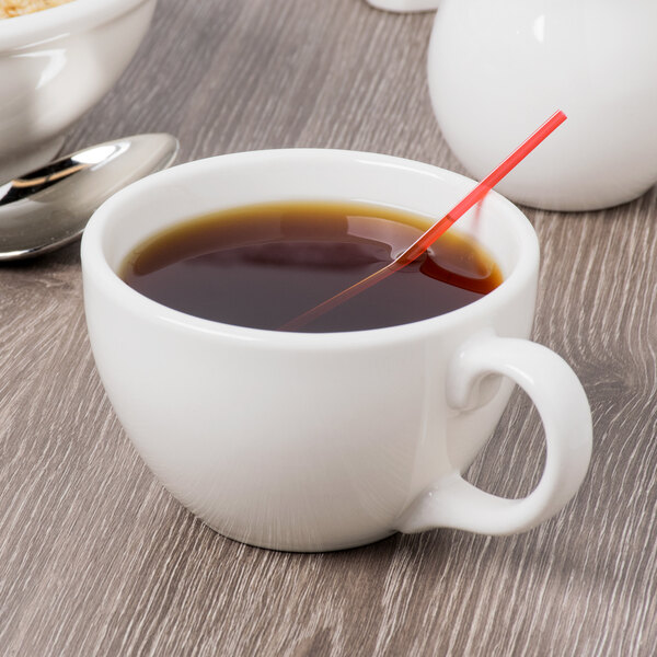 A Libbey ivory porcelain coffee cup filled with coffee and a spoon.