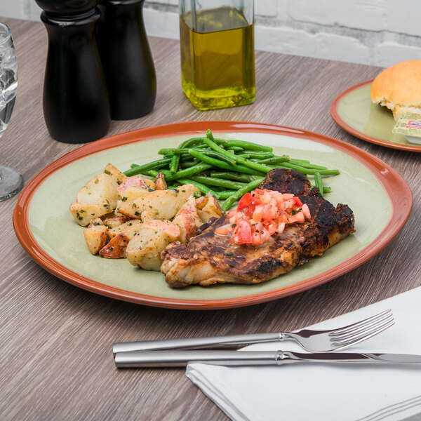A Libbey terracotta plate with meat, potatoes, and green beans.