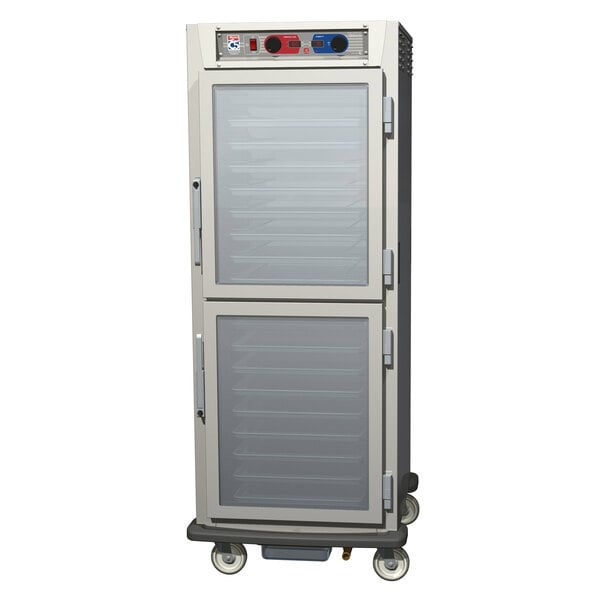 A stainless steel Metro C5 holding/proofing cabinet with clear Dutch doors on wheels.