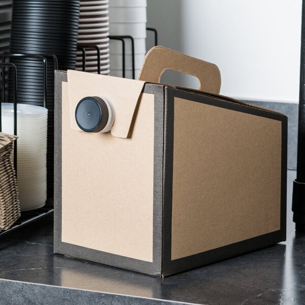 A brown Sabert coffee take out container box with a black lid on a counter.