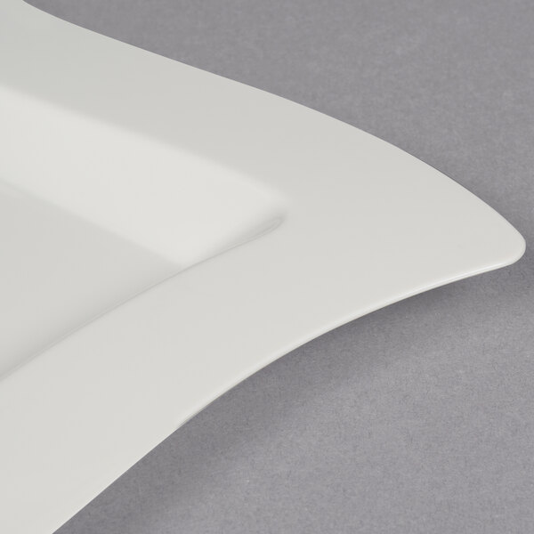 A close up of a Fineline bone ivory square plate with a curved edge.