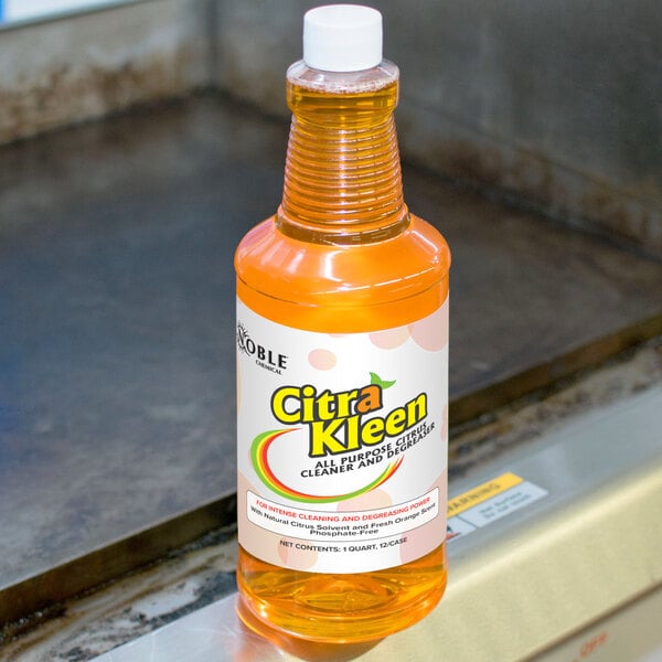 A bottle of Noble Chemical CitraKleen orange liquid on a counter in a professional kitchen.