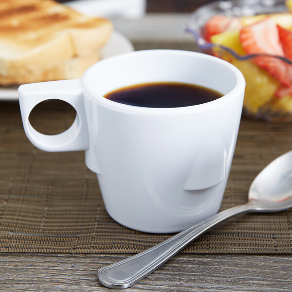 A white melamine cup of coffee on a saucer with a spoon.