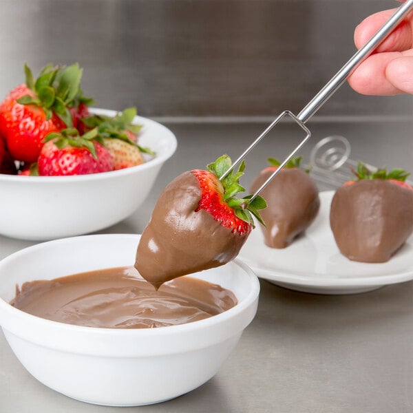 a person holding a chocolate dipped strawberry