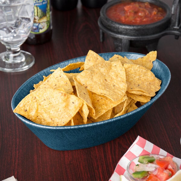 A blue oval basket of chips on a table in a Mexican restaurant.