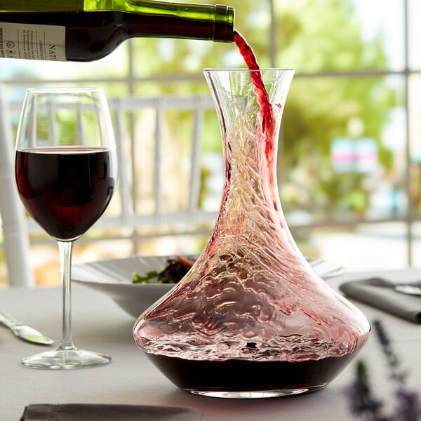 Glass decanter being filled with red wine