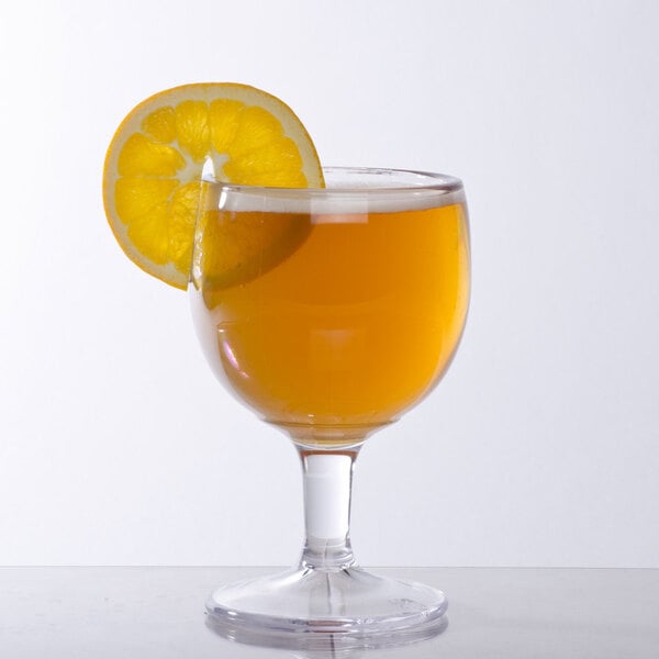 A customizable GET SAN plastic schooner filled with orange juice with a slice of orange on the rim.