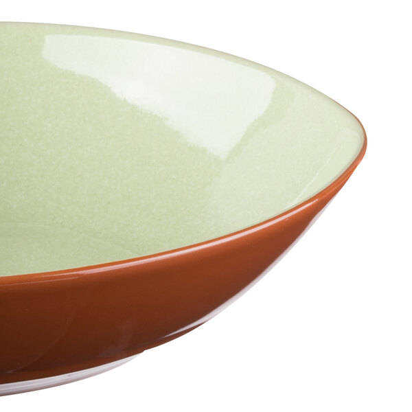 A close up of a Libbey terracotta bowl with a green and brown rim.