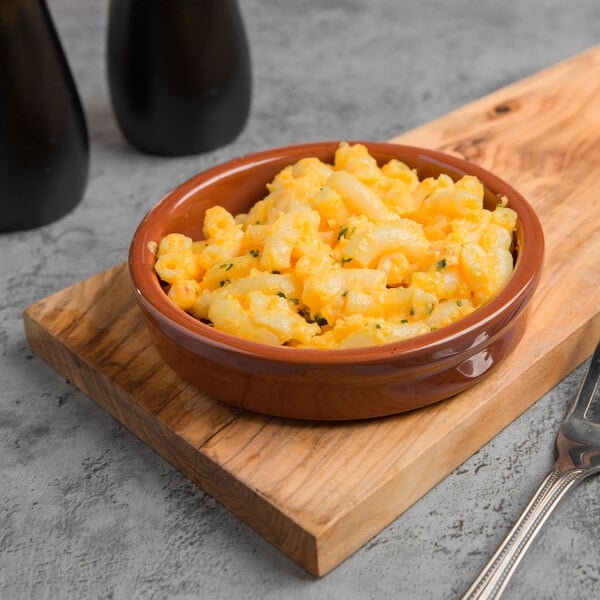 A Libbey terracotta cazuela bowl filled with macaroni and cheese on a table.