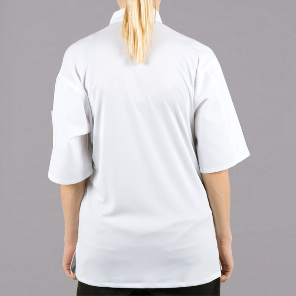 A woman wearing a white Mercer Culinary Millennia Air chef jacket with a full mesh back.